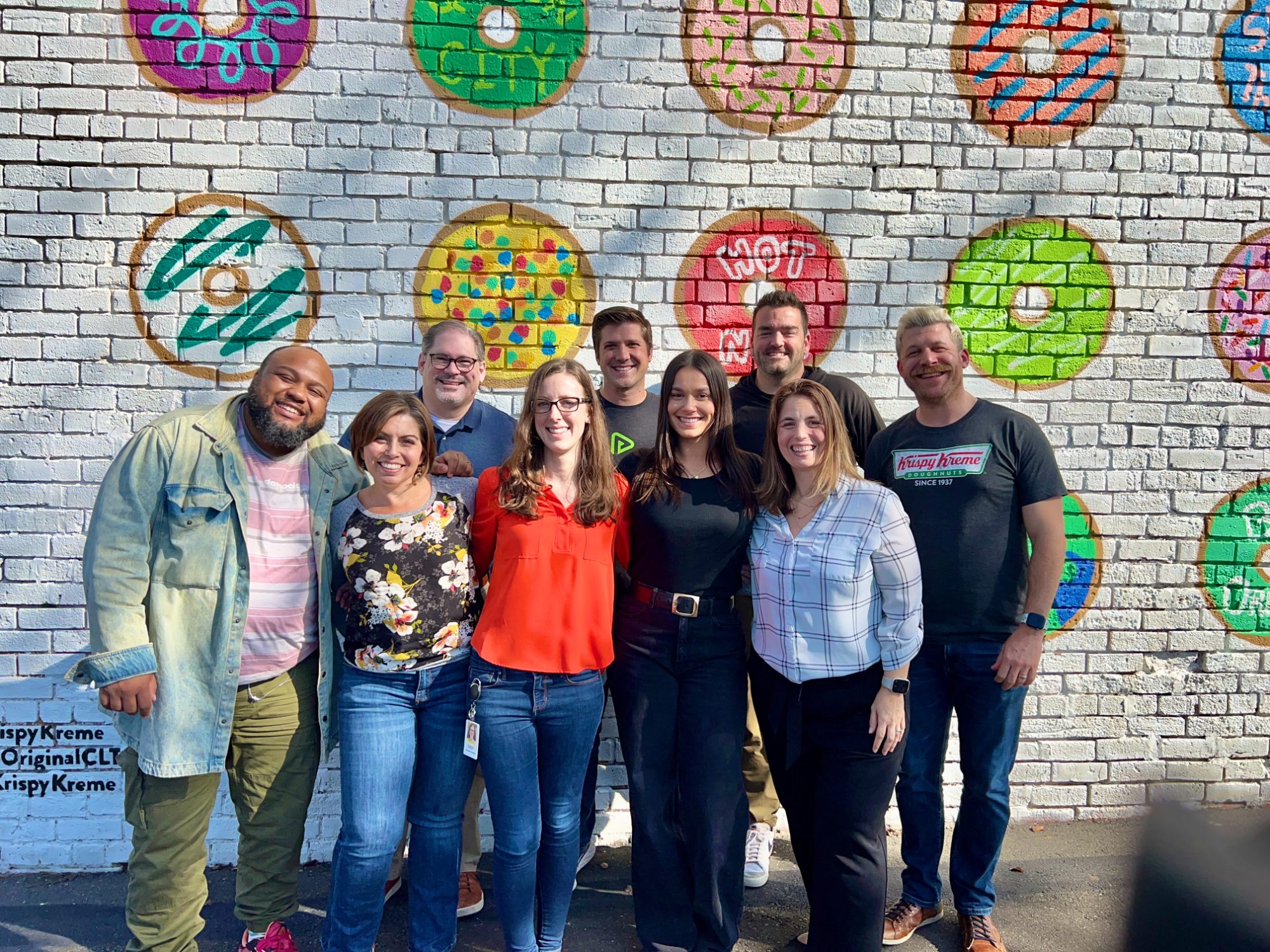 The Modern Training team together in front of a colorful Krispy Kreme doughnut mural