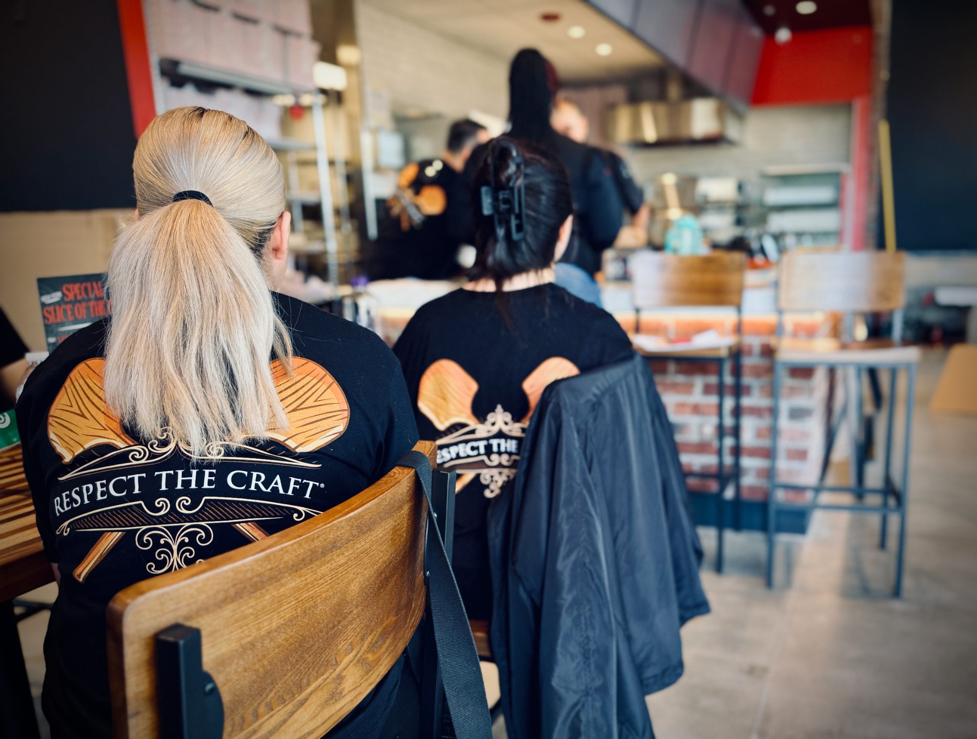 Team members in 'Respect the Craft' shirts watching a kitchen training session at a new restaurant
